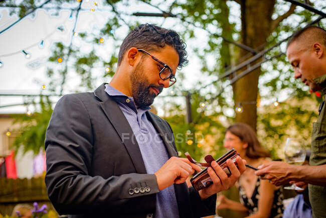 Zwei Männer bei Gartenparty mit Blick aufs Smartphone — Stockfoto
