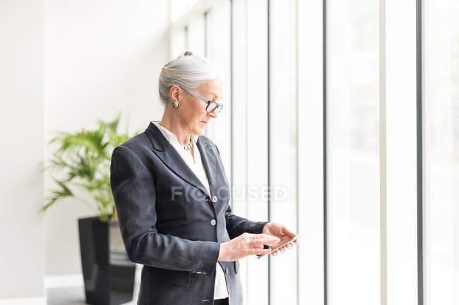 Reife Geschäftsfrau schaut aufs Smartphone — Stockfoto