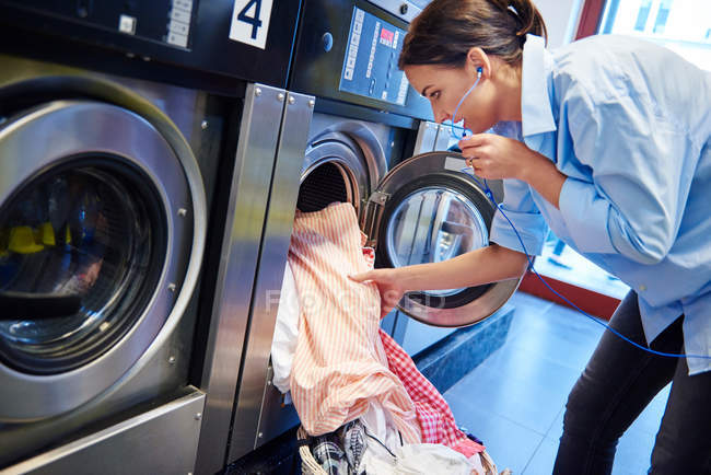 Femme insérant la buanderie dans la machine à laver — Photo de stock