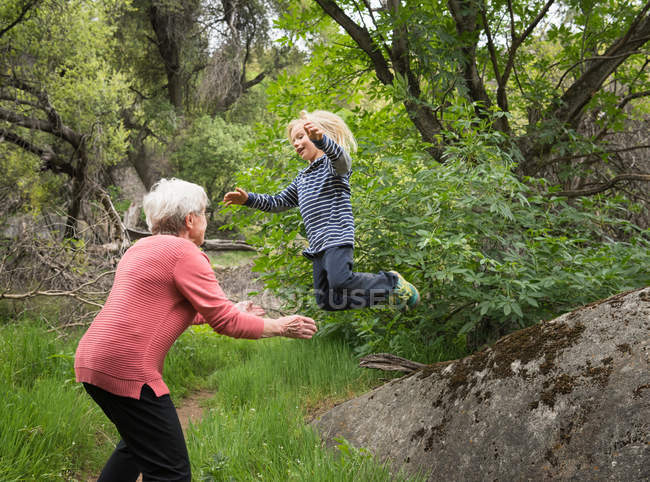 Grandson jumping off rock — Stock Photo