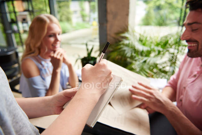 Camarera escribiendo orden de pareja - foto de stock