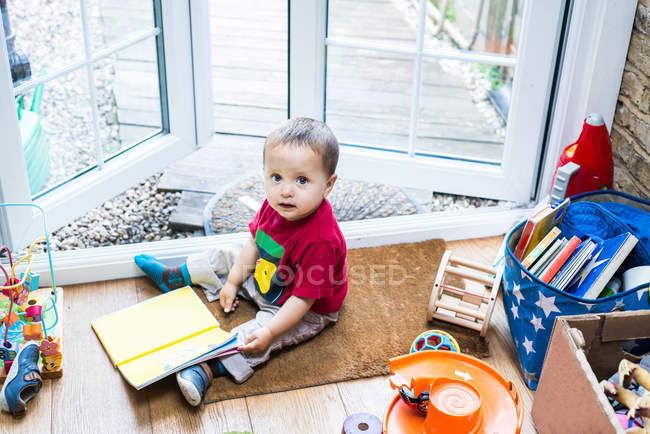 Niño sentado en la alfombra de la puerta - foto de stock