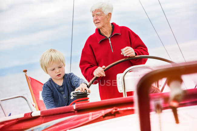 Boy with great grandfather on sailing boat — Stock Photo