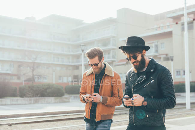 Hipsters looking at smartphones — Stock Photo