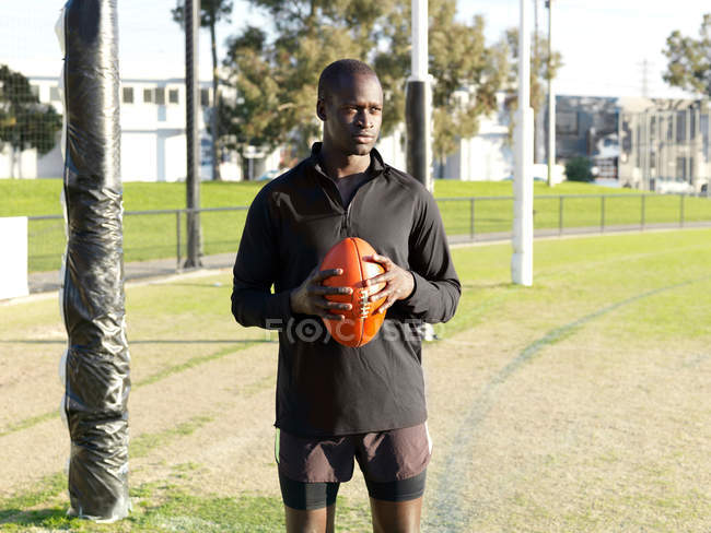Jogador de rugby segurando bola no campo — Fotografia de Stock