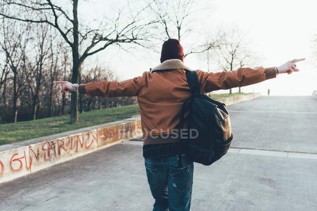 Hipster walking in park with arms out — Stock Photo