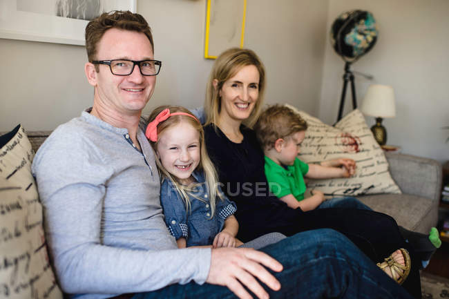 Родители сидят на диване с детьми — стоковое фото