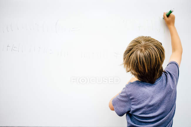 Молодий хлопчик пише на дошці — стокове фото