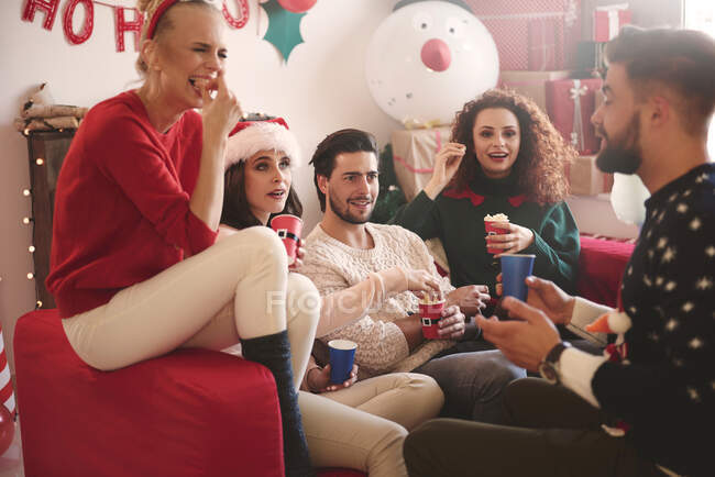 Jovens mulheres e homens comendo pipocas no sofá na festa de Natal — Fotografia de Stock