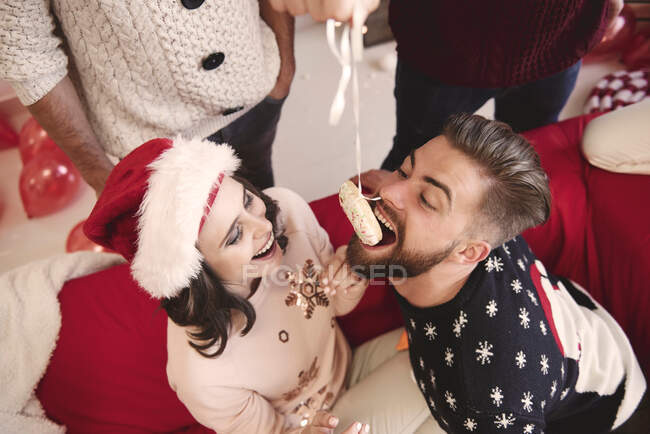 Vue aérienne du jeune homme mangeant un beignet pendu à la fête de Noël — Photo de stock