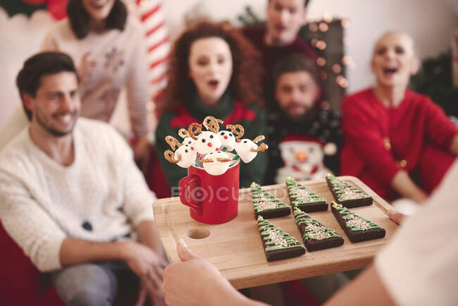Sopra la spalla vista di giovane donna che serve amici con biscotti di Natale alla festa di Natale — Foto stock