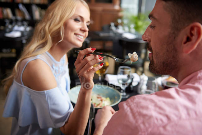 Woman feeding boyfriend lunch — Stock Photo