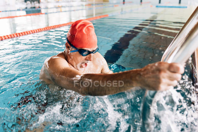 Homem usando escada na piscina — Fotografia de Stock