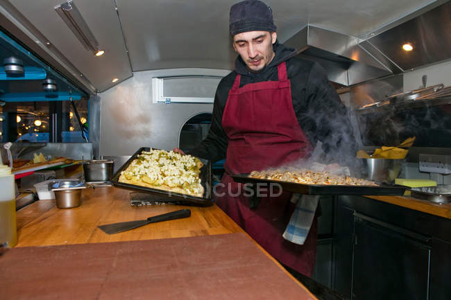 Homem preparando pizzas em van de barracas de comida à noite — Fotografia de Stock