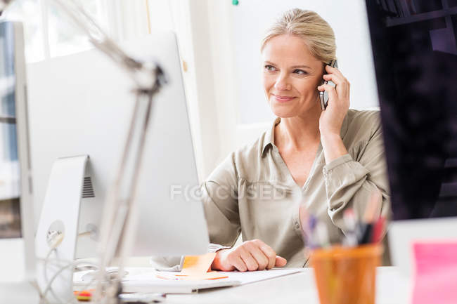 Diseñadora femenina haciendo llamada de teléfono inteligente - foto de stock