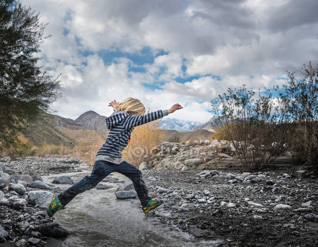 boy leaping over rocks