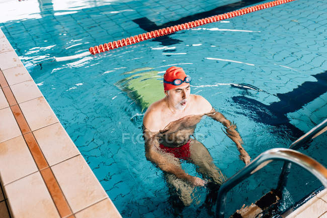 Man using ladder in swimming pool — Stock Photo