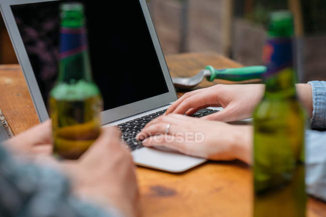 Casal beber cerveja e usando laptop — Fotografia de Stock
