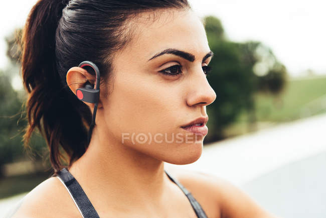Jeune femme à l'extérieur, portant des écouteurs — Photo de stock