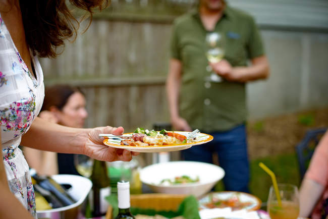 Frau bei Gartenparty hält Teller mit Essen — Stockfoto
