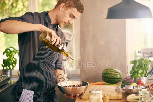 Koch träufelt Öl auf Schüssel — Stockfoto