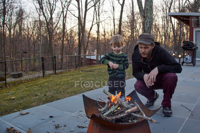 Boy and father tending fire — Stock Photo