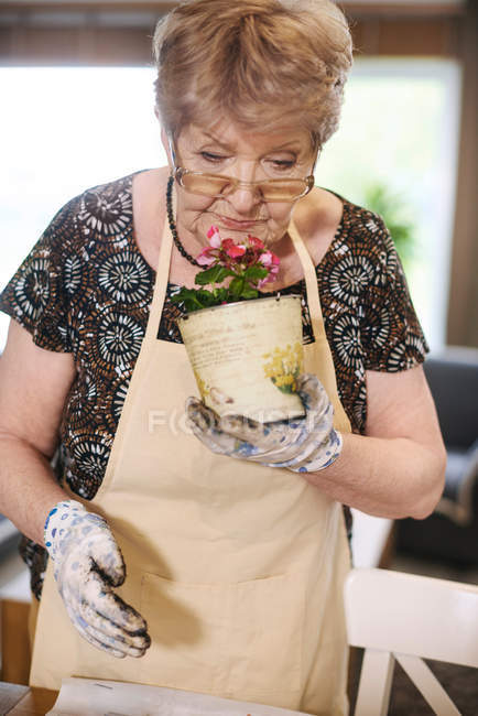 Femme sentant la plante en pot — Photo de stock