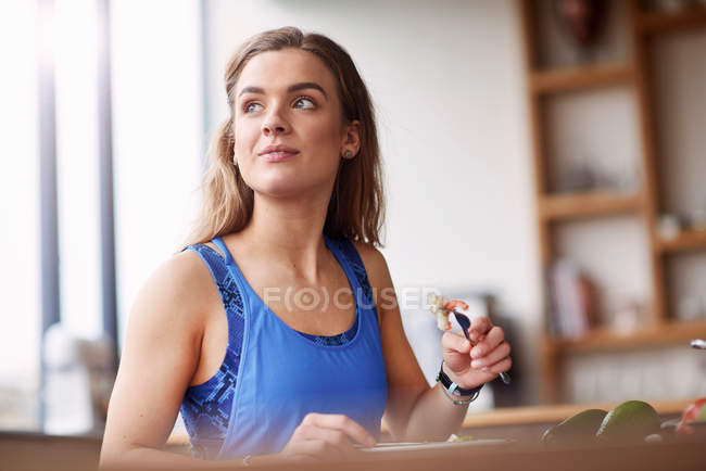 Mujer en cocina mesa comer feta - foto de stock