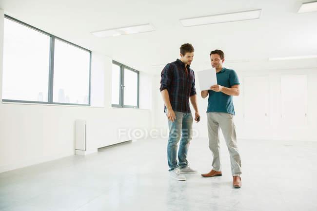 Hombres de pie en espacio de oficina vacío - foto de stock