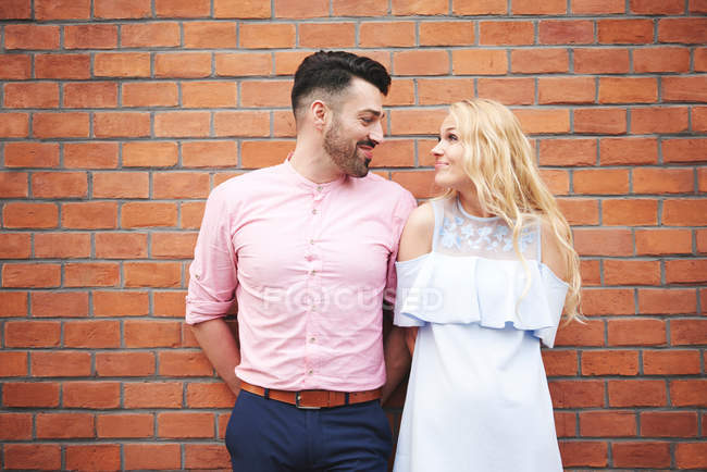 Couple in front of brick wall face to face — Stock Photo