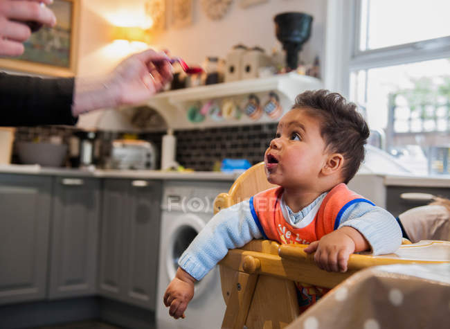 Bambino ragazzo in seggiolone essere alimentato — Foto stock