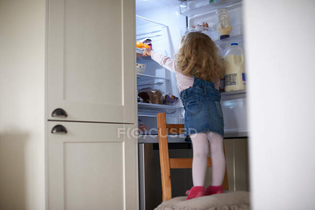 Young girl standing on chair — Stock Photo