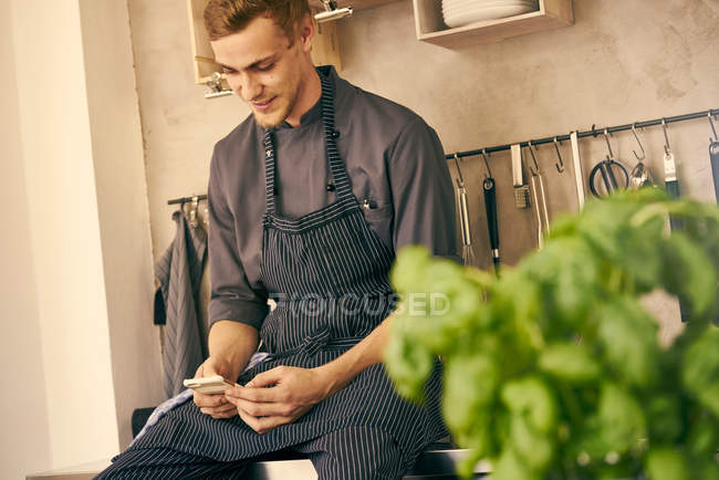 Chef in cucina guardando smartphone — Foto stock