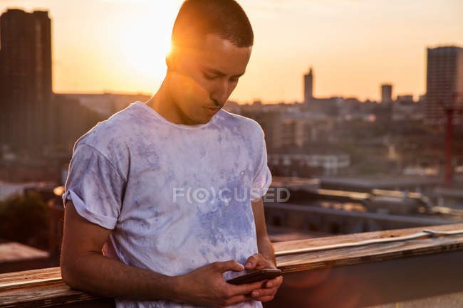 Чоловік дивиться на смартфон на заході сонця — стокове фото