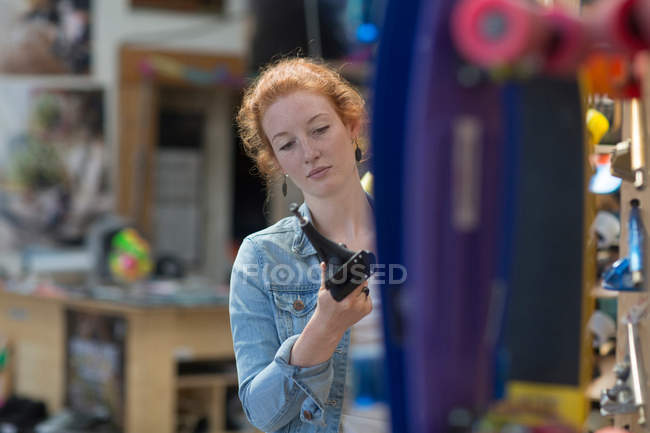 Femme travaillant dans un magasin de skateboard — Photo de stock