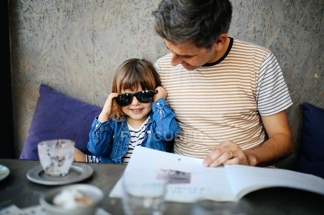 Girl playing with fathers sunglasses — Stock Photo
