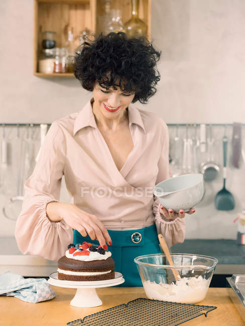 Женщина украшает шоколадный торт — стоковое фото