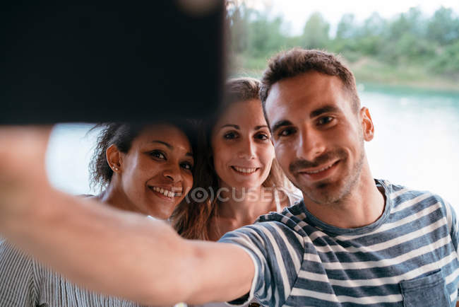 Tres amigos tomando selfie con smartphone - foto de stock