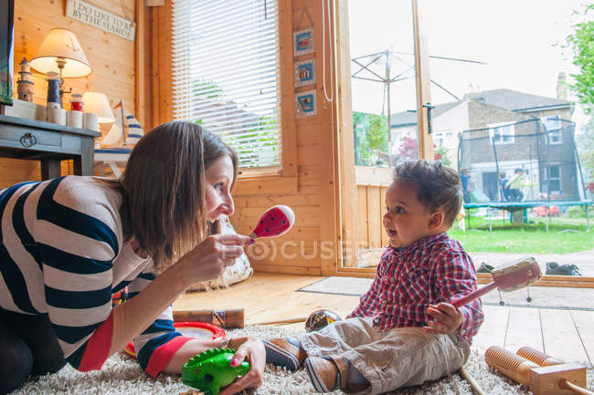 Childminder sacudindo maraca em menino — Fotografia de Stock