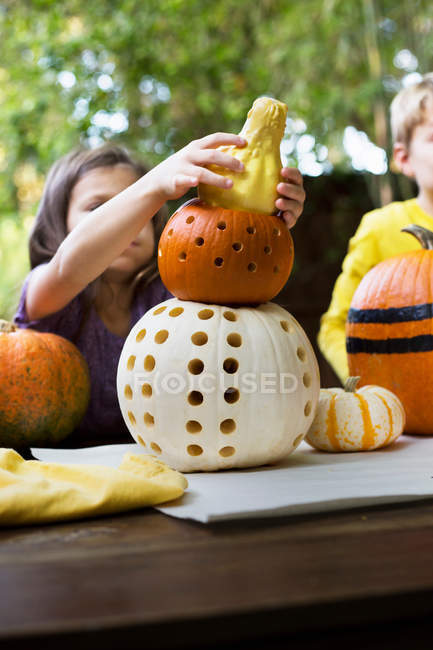 Girl and brother stacking carved pumpkins — Stock Photo