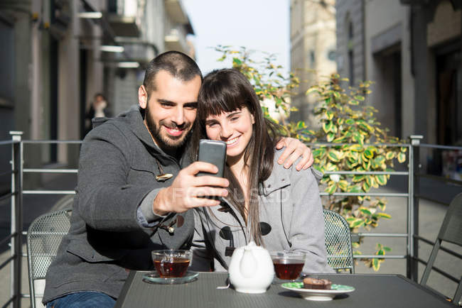 Молодая пара, сидящая снаружи кафе — стоковое фото