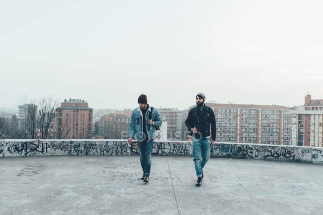 Hipsters masculins marchent sur la terrasse du toit de la ville — Photo de stock