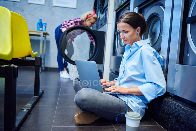 Femme assise sur le plancher de la laverie — Photo de stock