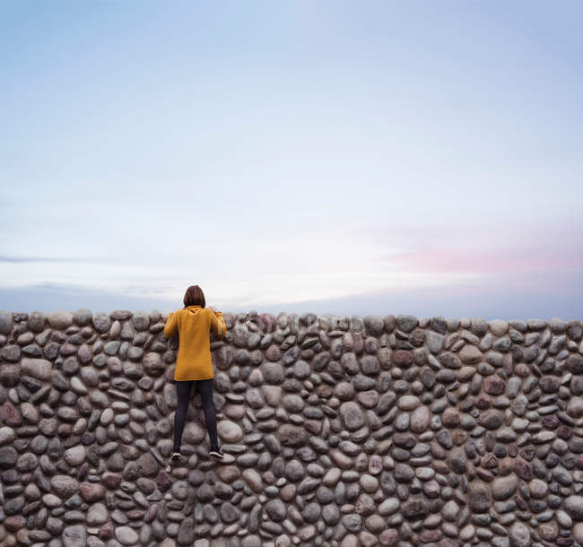 Femme tenant sur un mur de pierre — Photo de stock