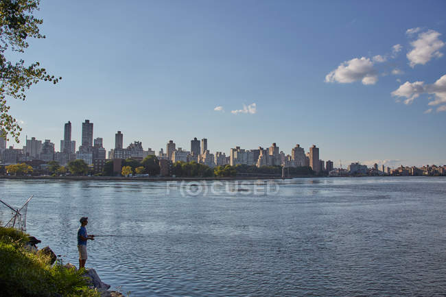 Adolescente menino pesca a partir da margem do rio — Fotografia de Stock