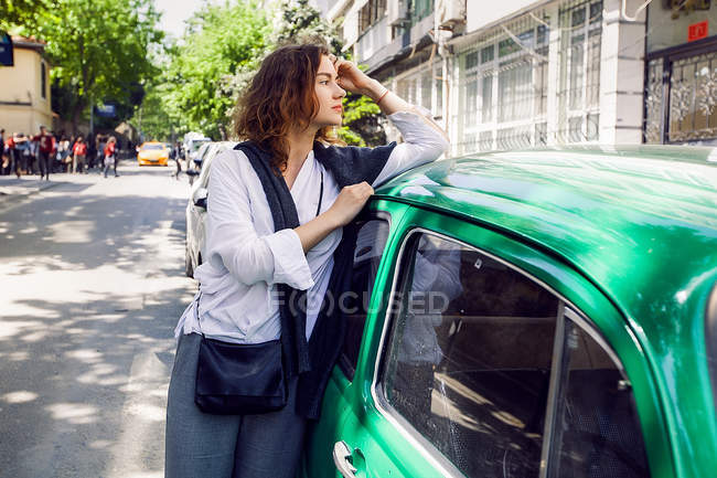 Donna accanto auto verde — Foto stock
