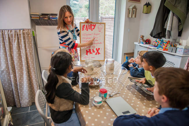 Childminder mostrando bambini ricetta artigianale — Foto stock
