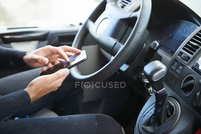 Человек, использующий смартфон в машине — стоковое фото