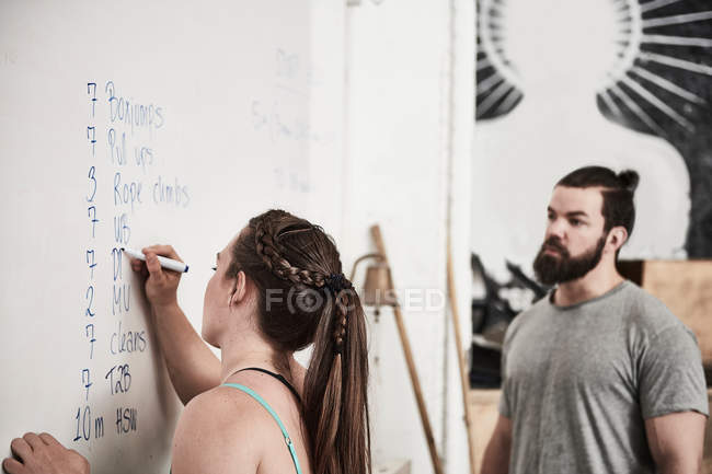 Istruttore di fitness che scrive sulla lavagna bianca — Foto stock