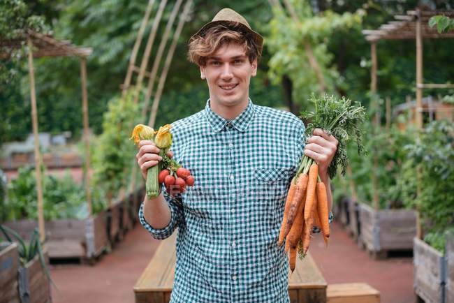 Homme tenant des grappes de carottes — Photo de stock